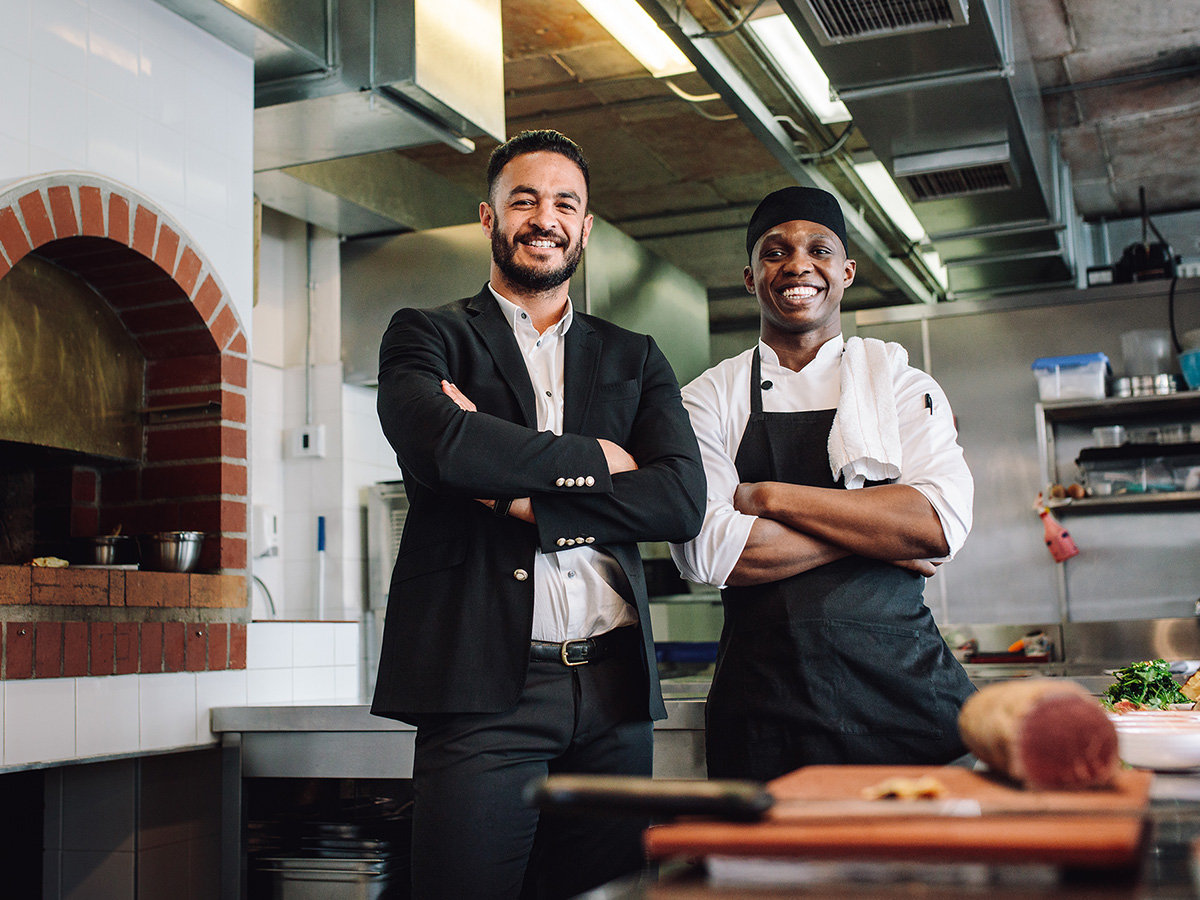 A restaurant owner and a head chef smiling